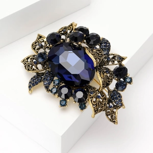 Detailed close-up of a vintage-style brooch with deep blue crystals on white marble pedestals