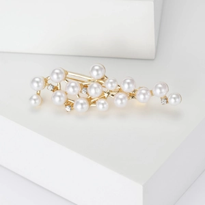 Detail shot of a golden branch hair clip featuring elegant pearls and sparkling rhinestones
