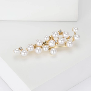 Detailed close-up of golden brooch with white pearls and sparkling rhinestones