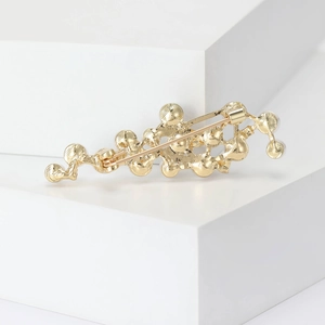 Elegant gold lava pearl brooch with abstract metallic fluid design on white blocks