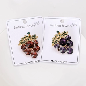 Detail of grape brooches with purple and red crystals on white display cards