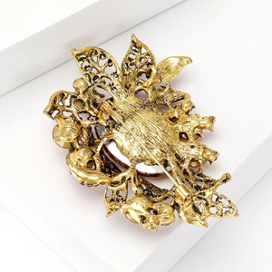 Elegant gold vintage flower brooch with zircon and red stones in back detail view