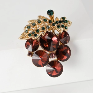 Macro shot of vintage grape brooch with wine red crystals and green encrusted leaves