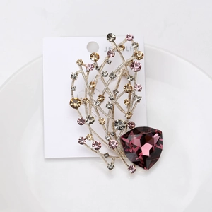 Détail d'une broche avec pierre précieuse violette en cœur et motifs de fleurs scintillantes
