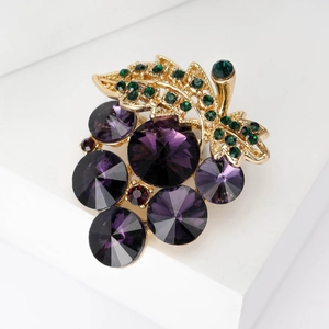 Macro view of crystal grape brooch with purple stones and green rhinestones on gold base