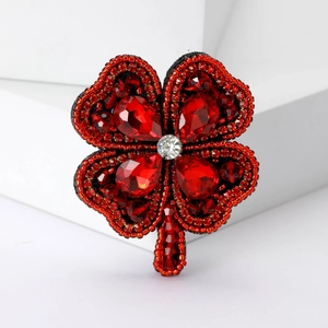 Vue macro détaillée d'une broche trèfle à quatre feuilles rouge faite à la main