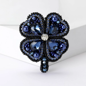Détail macro d'une broche trèfle faite main avec perles de cristal bleu et nacres