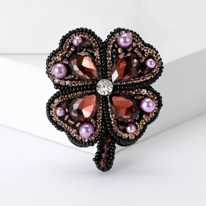 Broche trèfle élégante avec perles noires et cristaux violets sur fond blanc