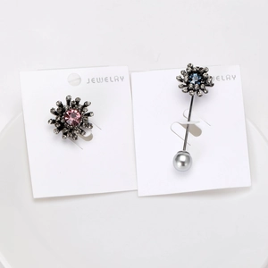 Detail of gunmetal floral brooches with pink crystals and blue gems on white card