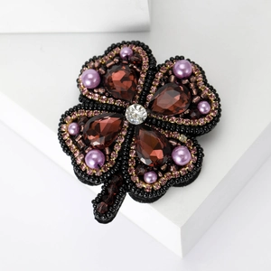 Vue macro d'une broche trèfle à quatre feuilles avec cristaux, perles et perlage