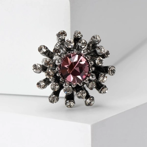 Detailed macro view of gun black vintage brooch featuring a large pink crystal and rhinestones