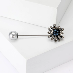 Detailed macro view of gun black brooch with deep blue crystal and grey pearl inlay