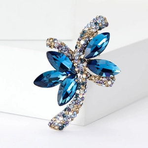 Macro di una spilla a fiore con cristallo blu navy e pavé di zirconi su piedistallo bianco