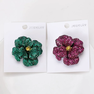 Detail view of flower brooch set with green and pink crystals on jewelry display card