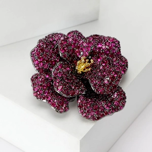 Macro detail of camellia brooch with ruby-pink pavé stones and golden core texture