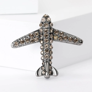 Gros plan sur la broche avion ornée de strass champagne sur un support en métal gris