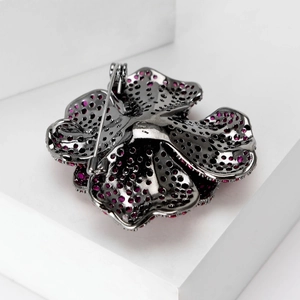 Back view of camellia brooch with pink zircons and black metal pin on white prop