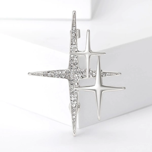 Gros plan d'une broche étoile argentée sertie de strass sur un socle géométrique blanc