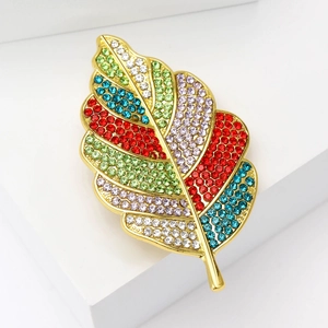 Broche feuille dorée tendance avec strass colorés sur un support géométrique blanc