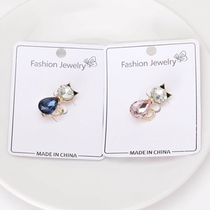 Dettaglio macro di eleganti spille a gattino con cristalli blu e rosa su espositore bianco