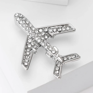 Broche avion argentée élégante sertie de cristaux brillants sur support blanc
