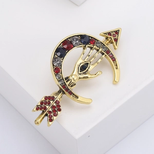 Dettaglio di spilla vintage dorata con motivo luna e occhio con strass colorati