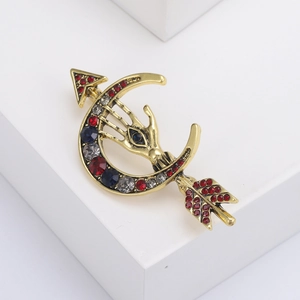 Dettaglio di spilla vintage a luna con occhio di palma in strass e freccia dorata