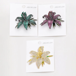 Détails de broches fleurs de lys en zircon en finitions verte, violette et argentée
