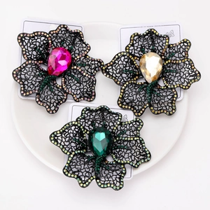 Detailed macro view of three vintage flower brooches with pink, green and champagne gems