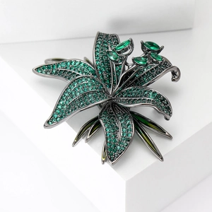 Détail d'une broche fleurie avec cristaux verts sertis sur un métal noir raffiné