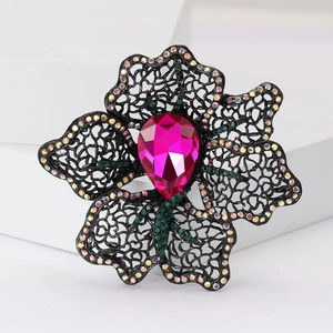Detailed macro of hollow lace flower brooch with rose pink crystal and colorful rhinestones