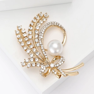 Macro detail of elegant golden wheat brooch with sparkling rhinestones and a white pearl
