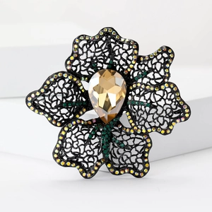 Elegant hollow flower brooch with amber crystal and black rhinestone petals on a white stand