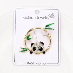 Macro shot of a panda brooch with green bamboo leaves and sparkling rhinestones
