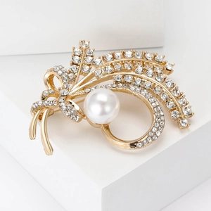 Macro detail of wheat ear brooch featuring a large white pearl and sparkling rhinestones