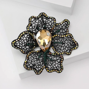 Floral hollow brooch with amber teardrop gemstone and colorful rhinestones on white block