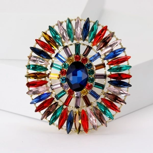 Detail view of colorful oval crystal brooch with blue center stone and gold plating