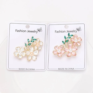 Detailed macro view of camellia pins with enamel petals, faux pearls, and green crystals