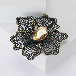 Detail of hollow black metal floral brooch with amber crystal and rhinestone accents