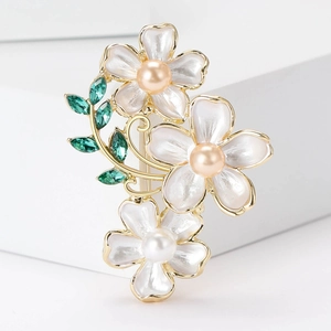 Detail of three white camellia flower brooches with pearls and olive green leaf crystals