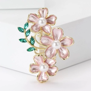 Elegant gold brooch featuring three pink enamel camellia flowers with white pearls and green leaves