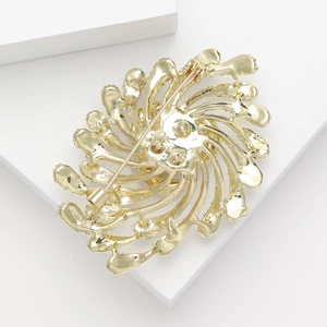 Elegant gold fireworks brooch with pearl and rhinestone inlay on white block stand