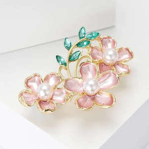 Detail of pink camellia brooch with white pearls and green crystal leaves on gold base