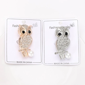 Détail de broches hibou de luxe avec strass et perles blanches en finitions dorée et argentée