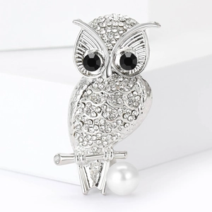 Vue détaillée d'une broche hibou en argent sertie de strass et d'une perle blanche