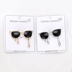 Macro detail of fashionable gold and silver sunglasses brooches with black enamel fluid design