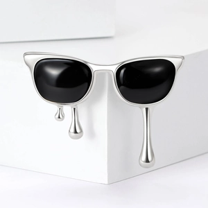 Detail of melting silver sunglasses brooch with liquid metal drops on white geometric stand