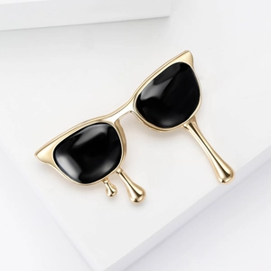 Creative gold cat-eye sunglasses brooch with black enamel inlay on a white pedestal