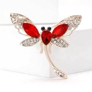Macro view showing the luxury dragonfly brooch with red rhinestones and gold plating details