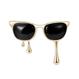 Artistic melting sunglasses brooch in gold finish with black enamel drip detail